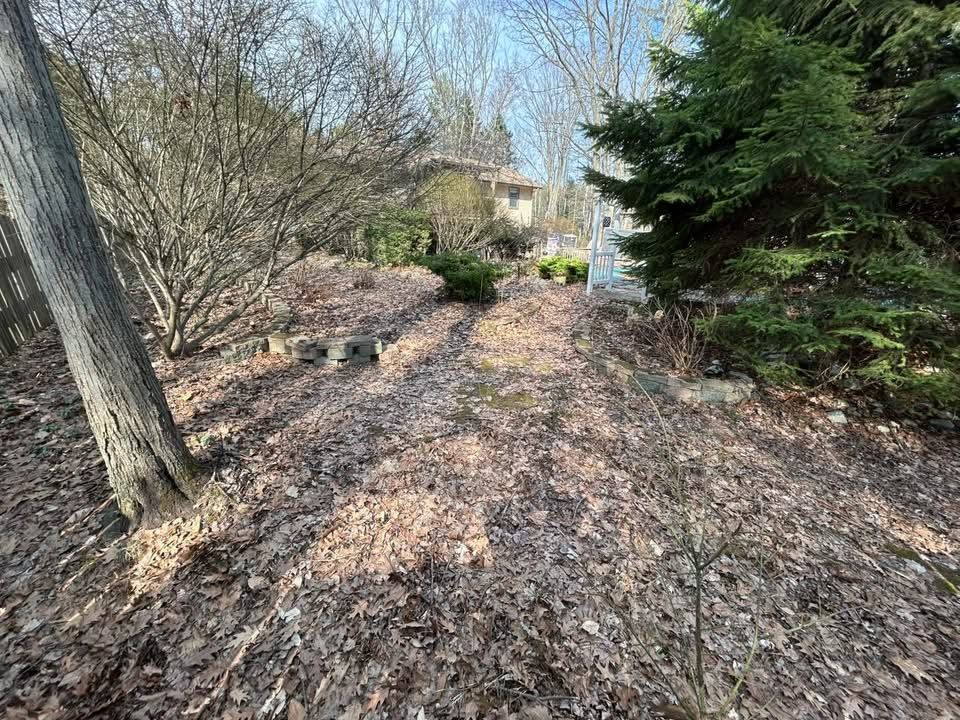 Before — garden bed covered in leaves and debris